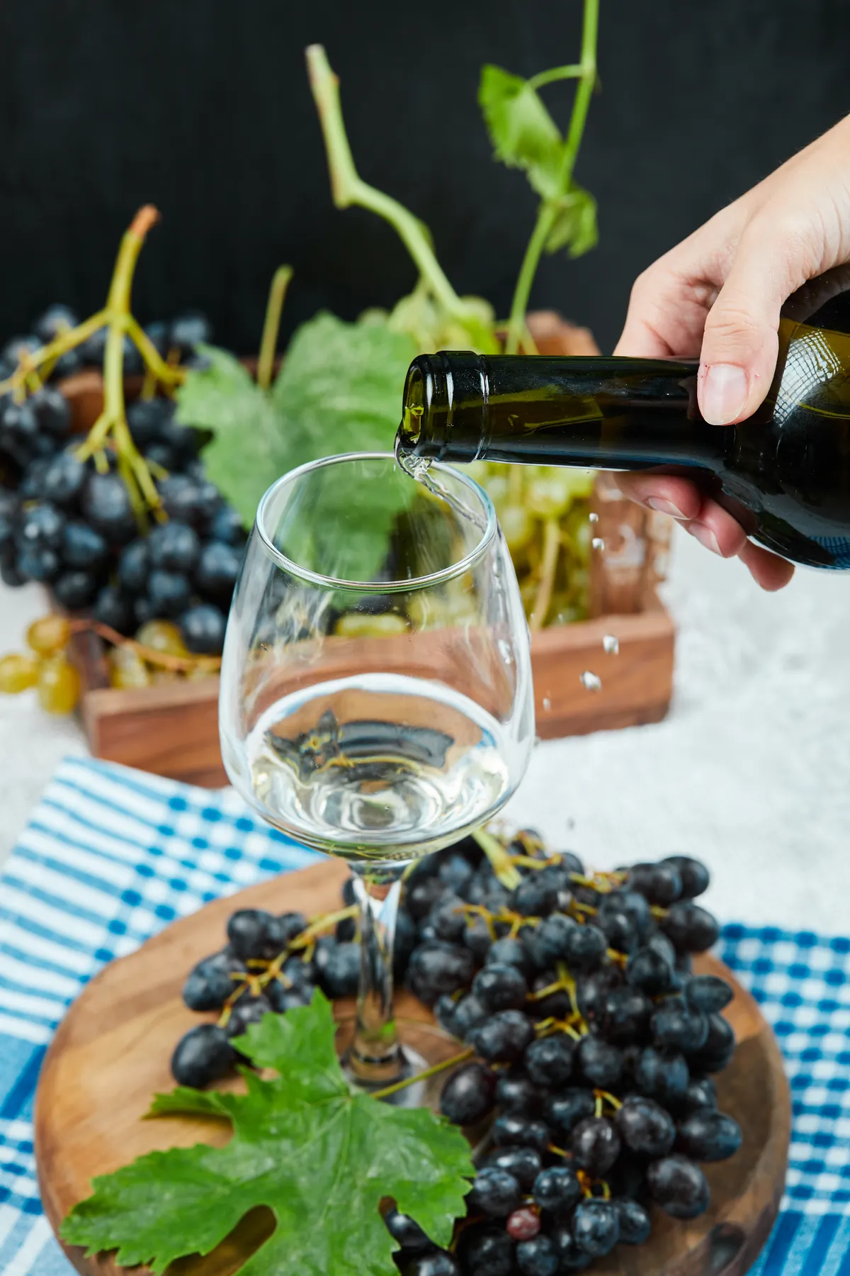 White wine being poured into a glass beside grapes
